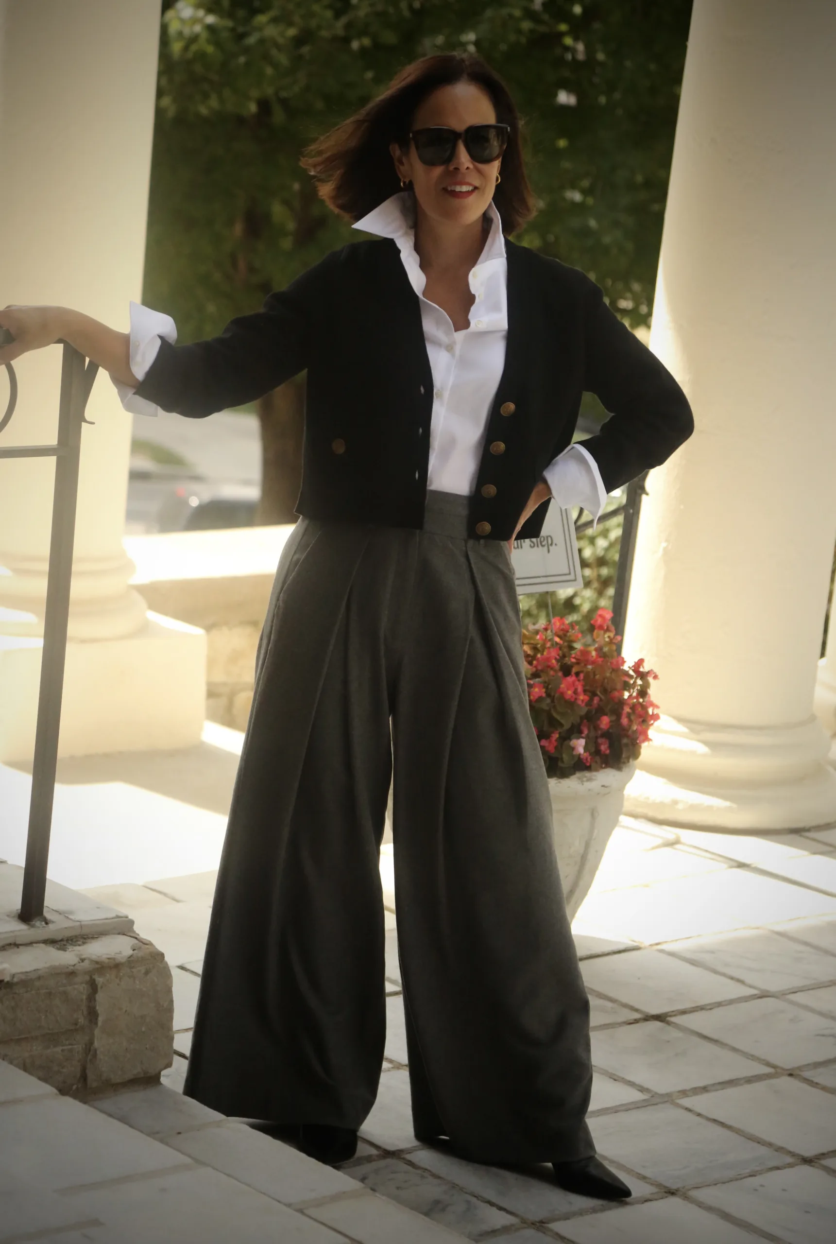 Woman wearing black cardigan with grey trousers standing against a staircase for elevated fall pieces at ME+EM