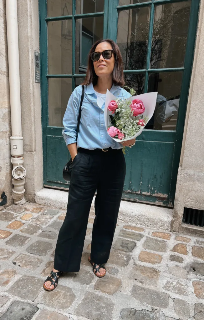 Woman holding flowers wearing black pants.