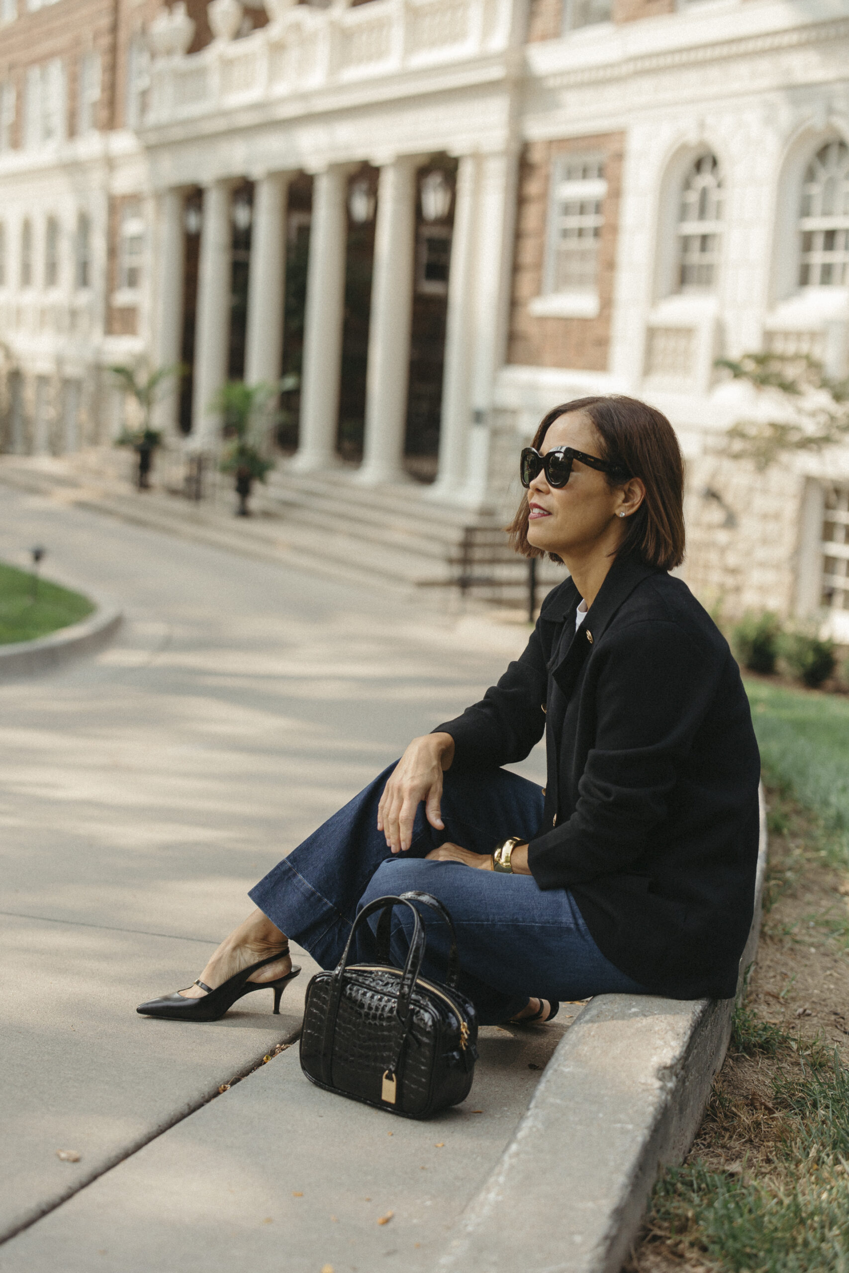 Woman sitting on curb wearing J.Crew sweater and jeans.