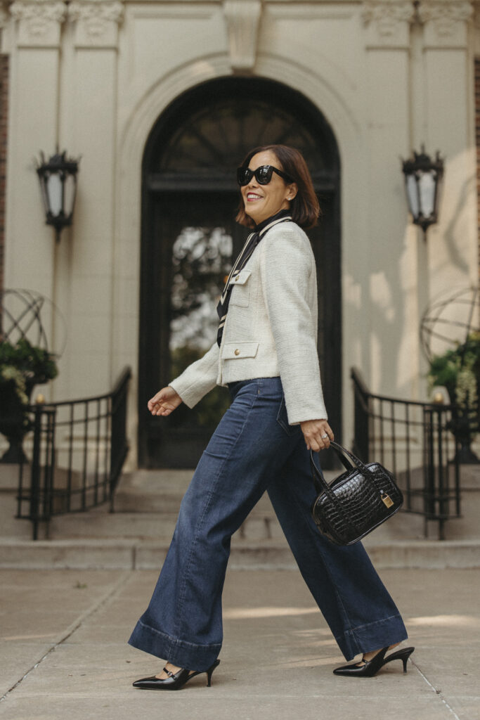 Woman in wide leg denim, tweed jacket and black slingbacks.