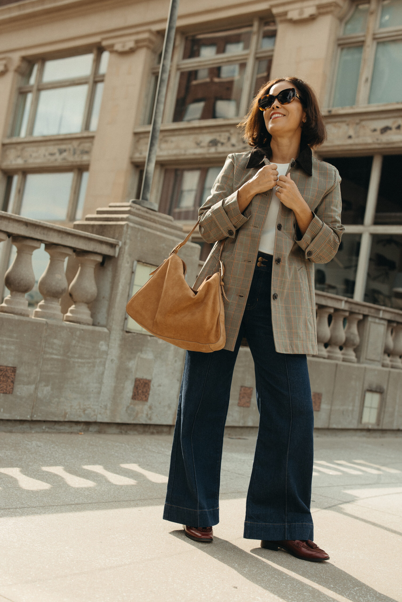 Woman wearing barn coat with denim and loafers.