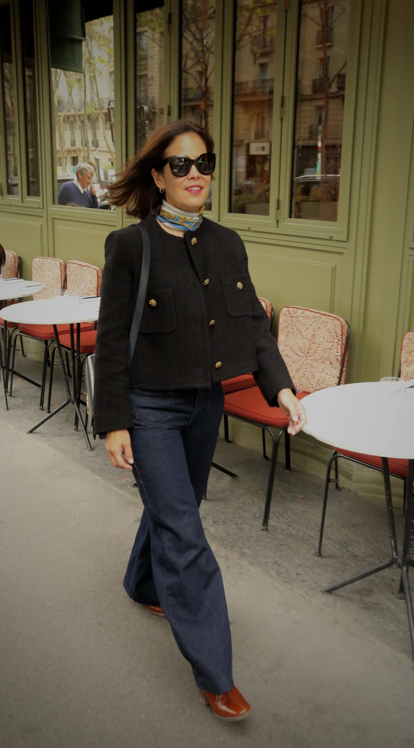 Woman walking wearing dark jeans, black jacket, and scarf | Paris Fall Outfits