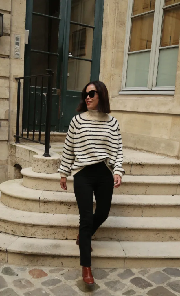 Woman coming down stairs in black jeans for parisian brunch outfit.