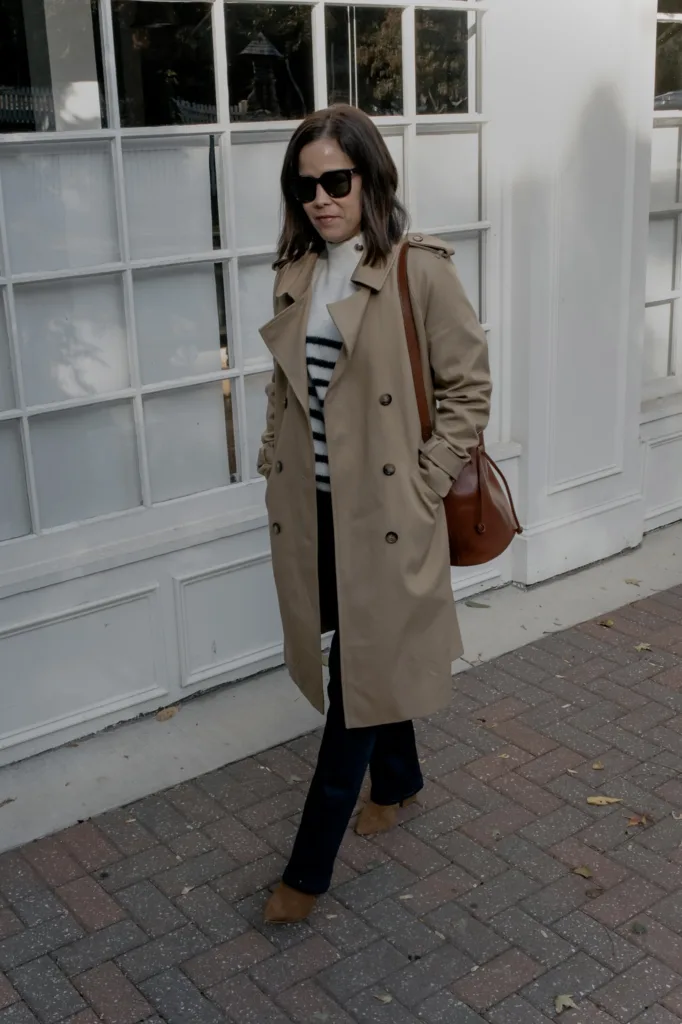 Woman wearing trench coat with jeans and boots.