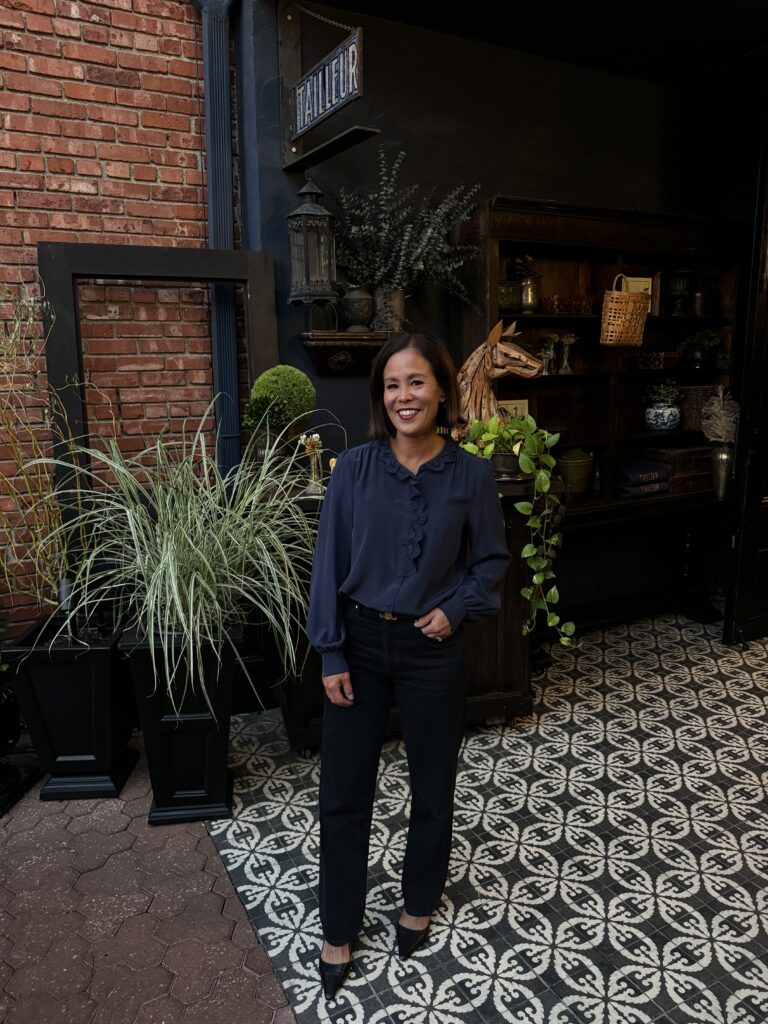 Woman wearing navy and black standing outside a restaurant.