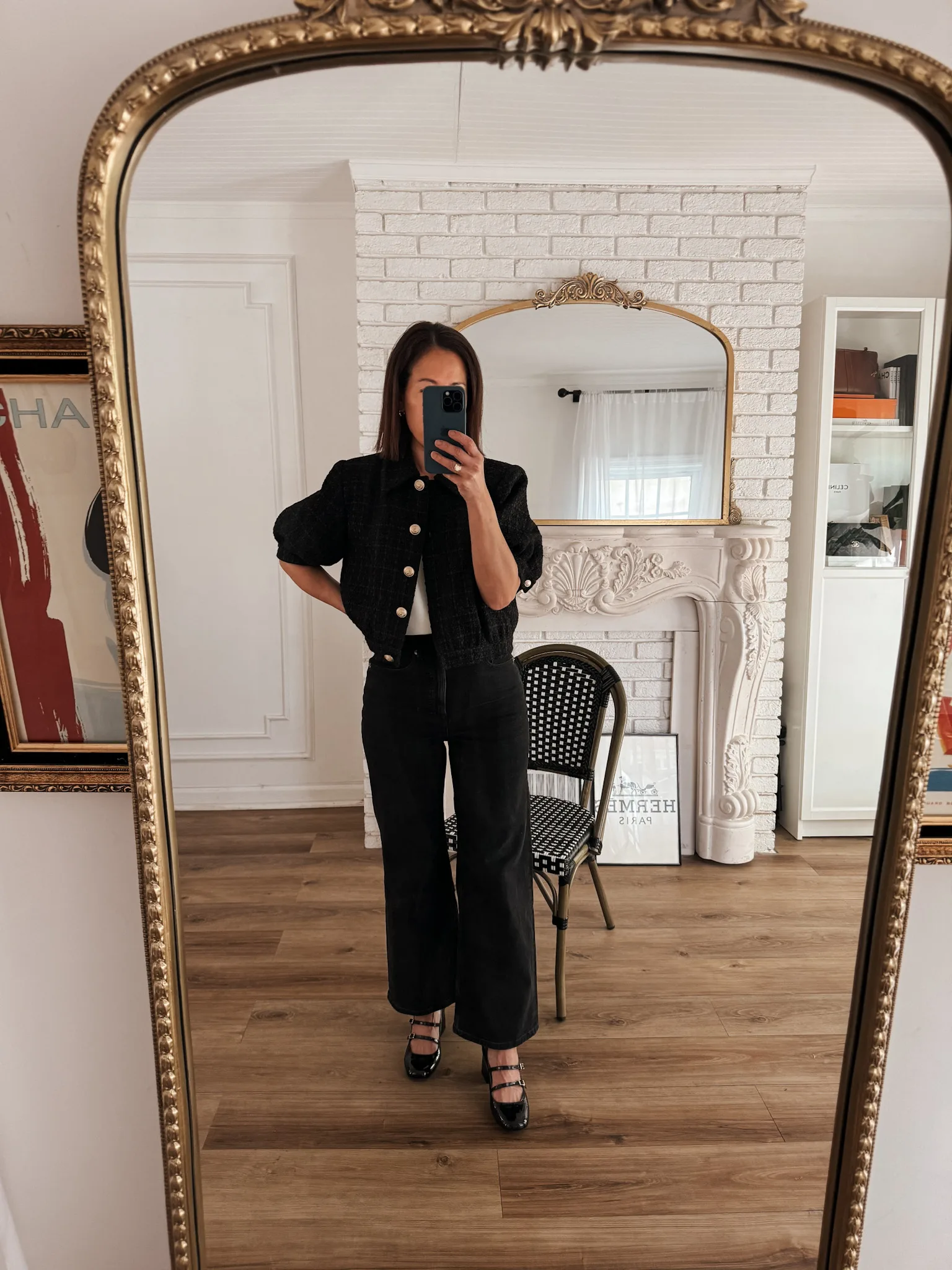 Woman looking in mirror wearing black tweed jacket with black mary jane shoes.