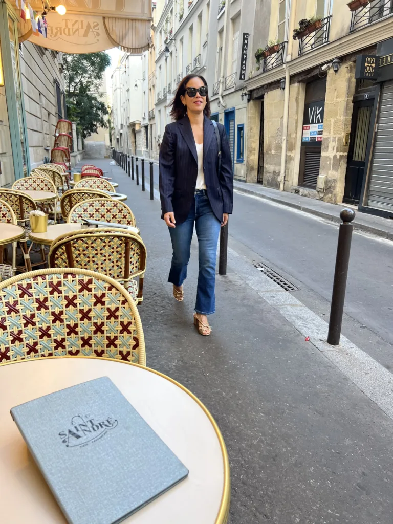 cafe in Paris Woman walking down street in Paris next to a cafe chair and table.