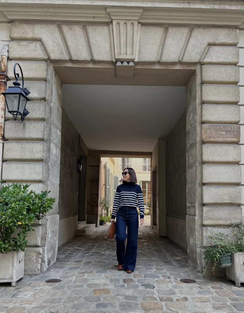 Paris october fashion Woman wearing stripe white and navy turtleneck with dark denim and boots.