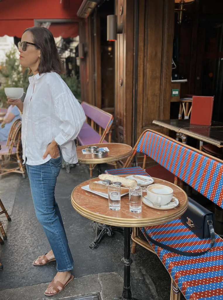 coffee in Paris Woman standing in white button down holding coffee in Paris.