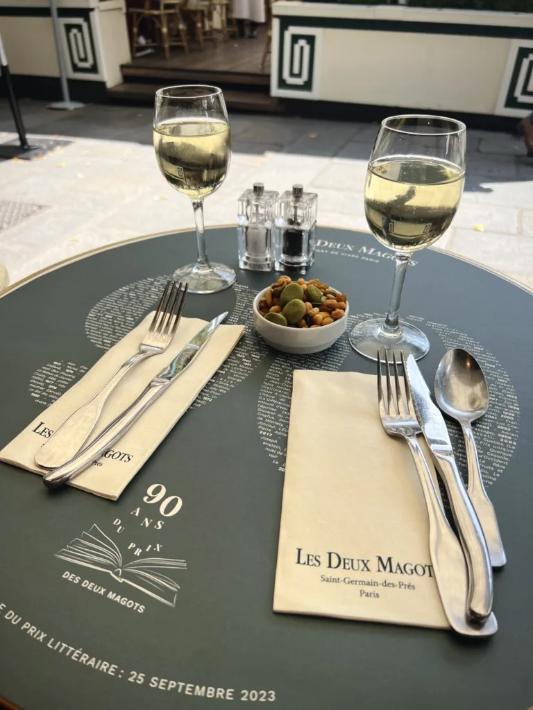 favorite parisian cafes wine glasses and nuts sitting on green table as favorite parisian cafes.