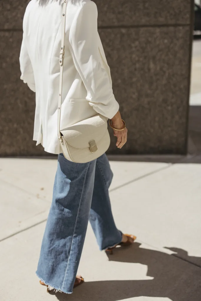 Woman in white blazer and denim with white sezane bag.