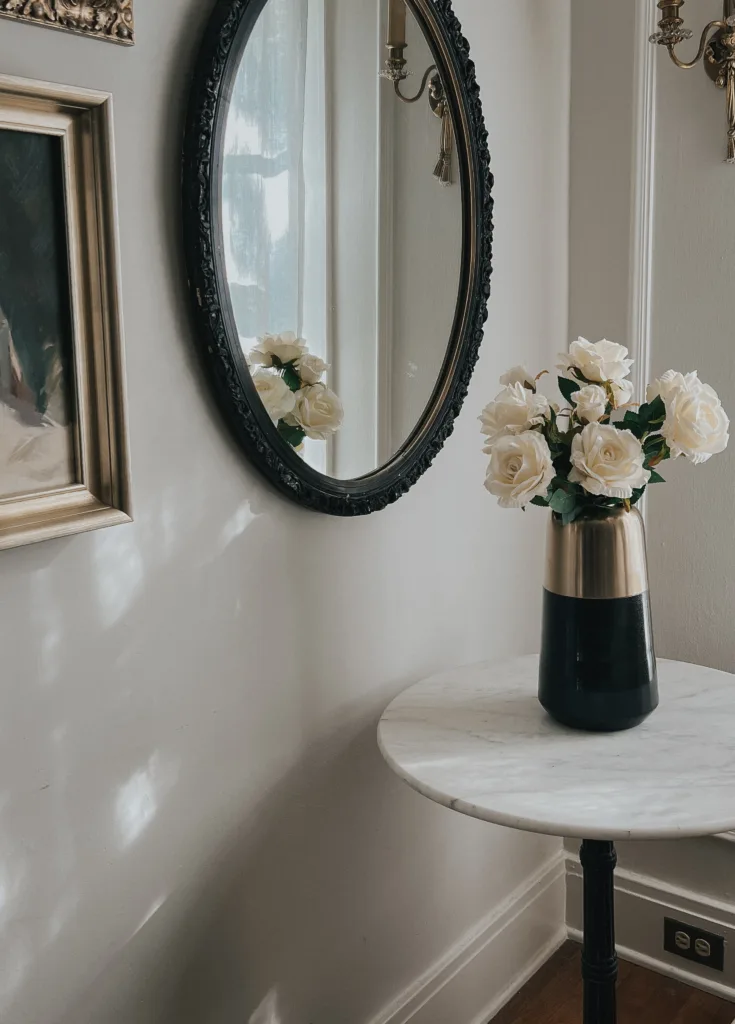 Marble table with black vase and fake roses with mirror.