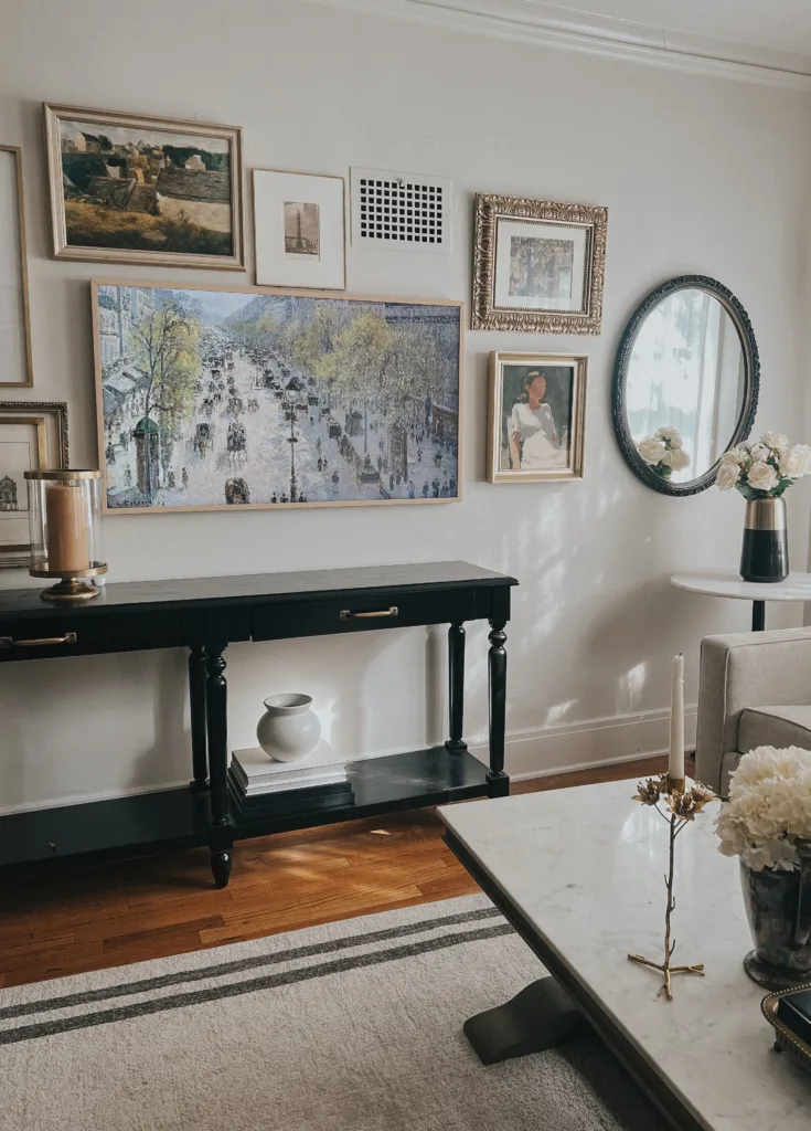 French art on interior wall with frame tv and black console.