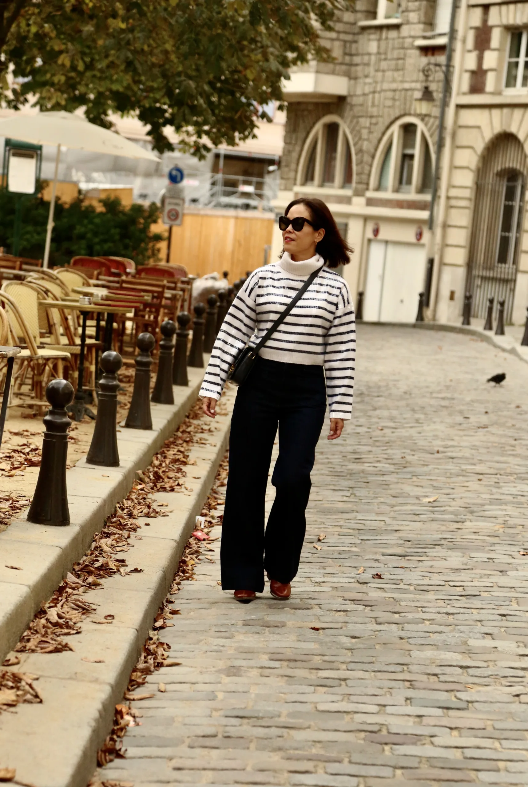 Woman with striped shirt walking in Paris.