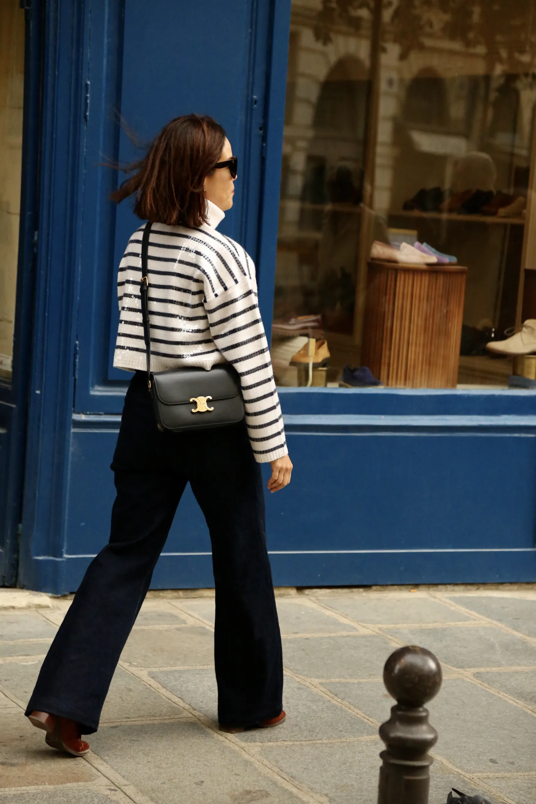 Woman in stripe navy an white top with dark denim in Paris.