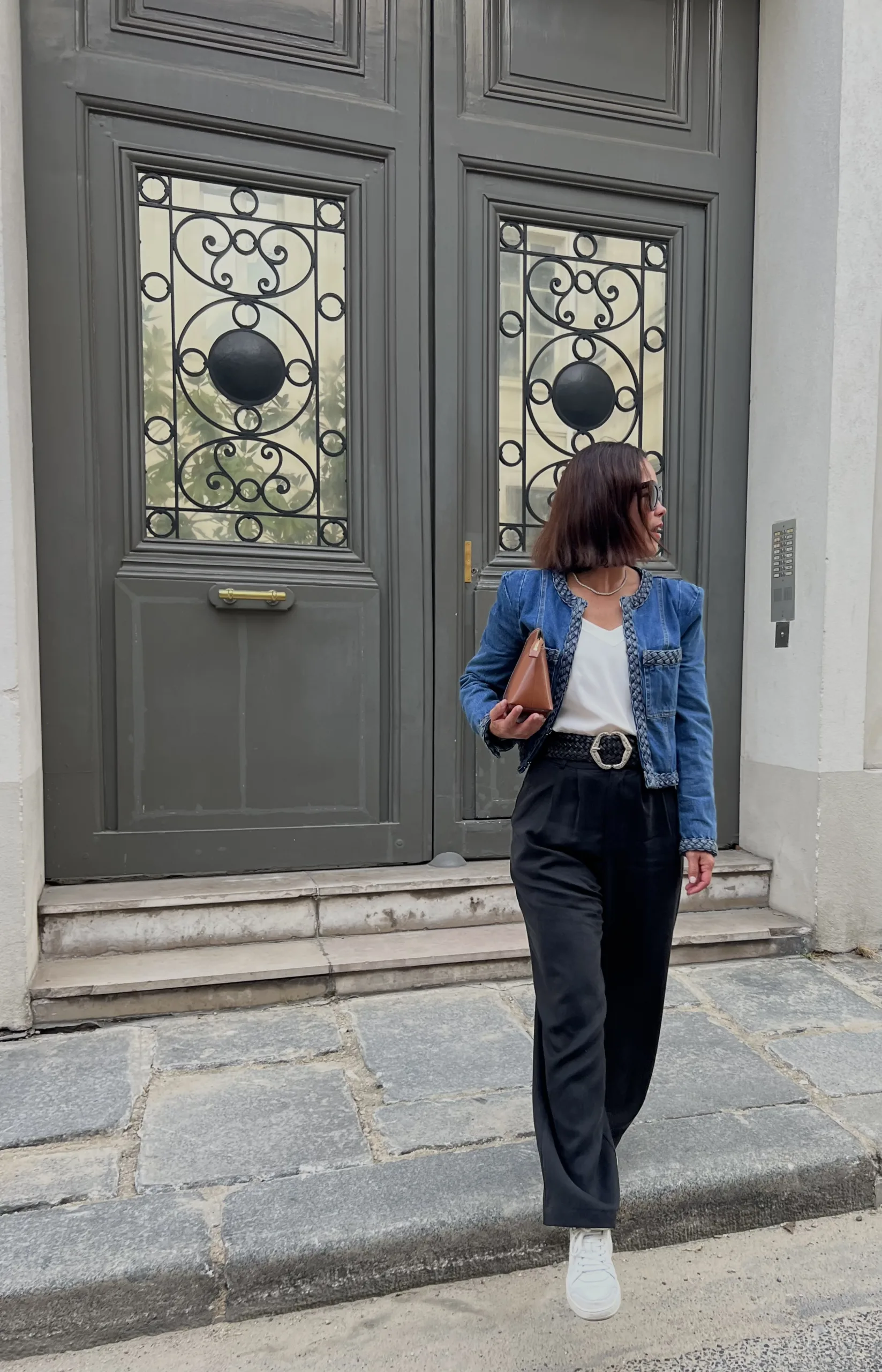 Woman in denim jacket with trousers on curb.