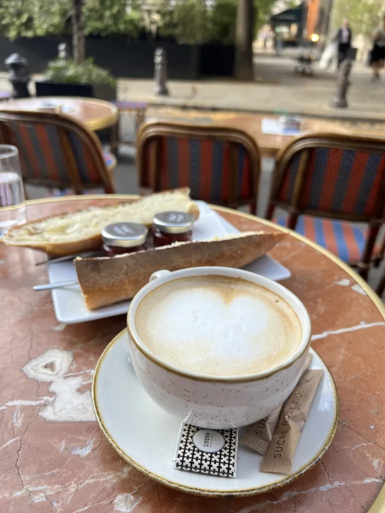 Coffee and table in Paris Cafe. How to pack for Paris in March to look classic and chic.