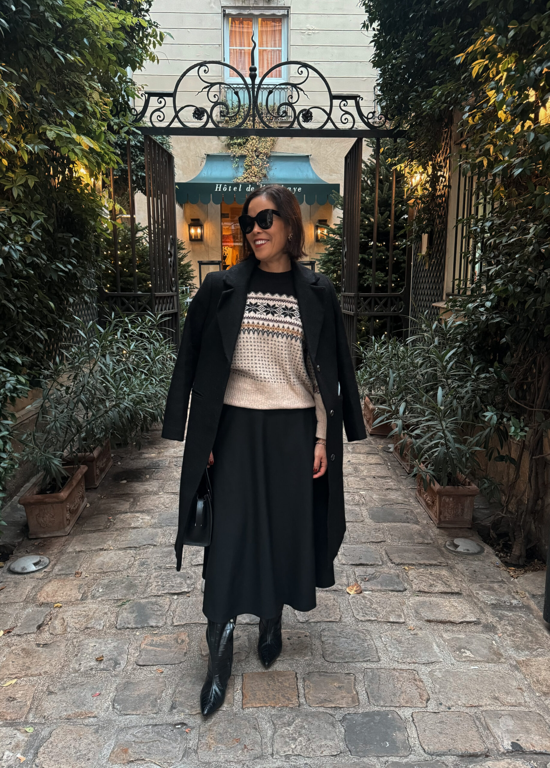 sweater with black skirt and coat Woman wearing sweater with black skirt and tall black boots in Paris in winter.