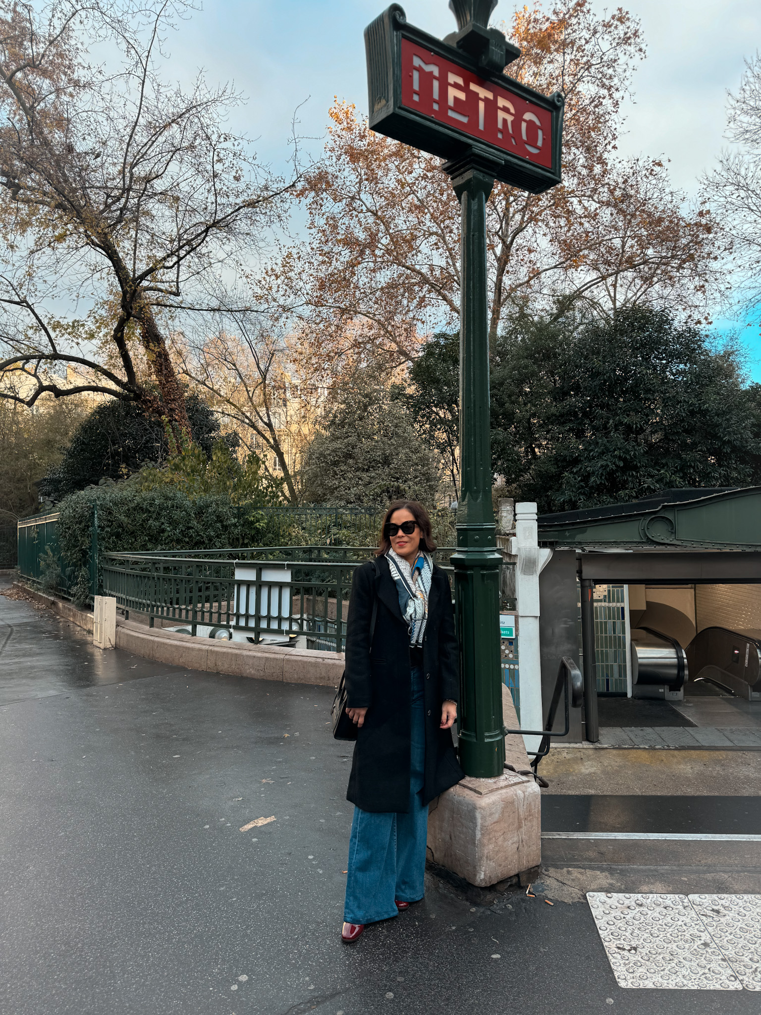 Woman standing next to metro sign in Paris in winter.