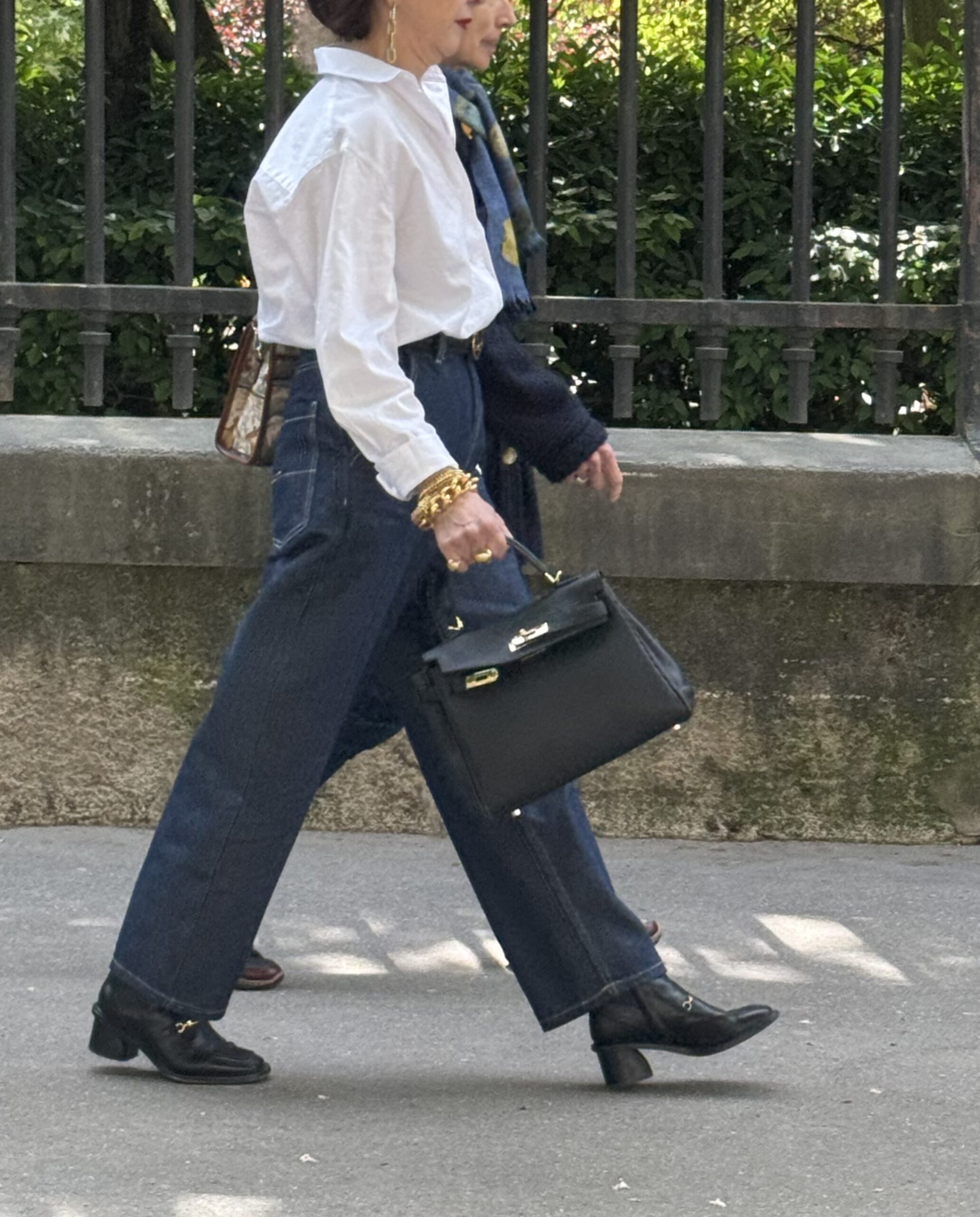 Woman walking down the street carrying a Hermès Kelly bag symbolizing heritage craftsmanship and French luxury fashion