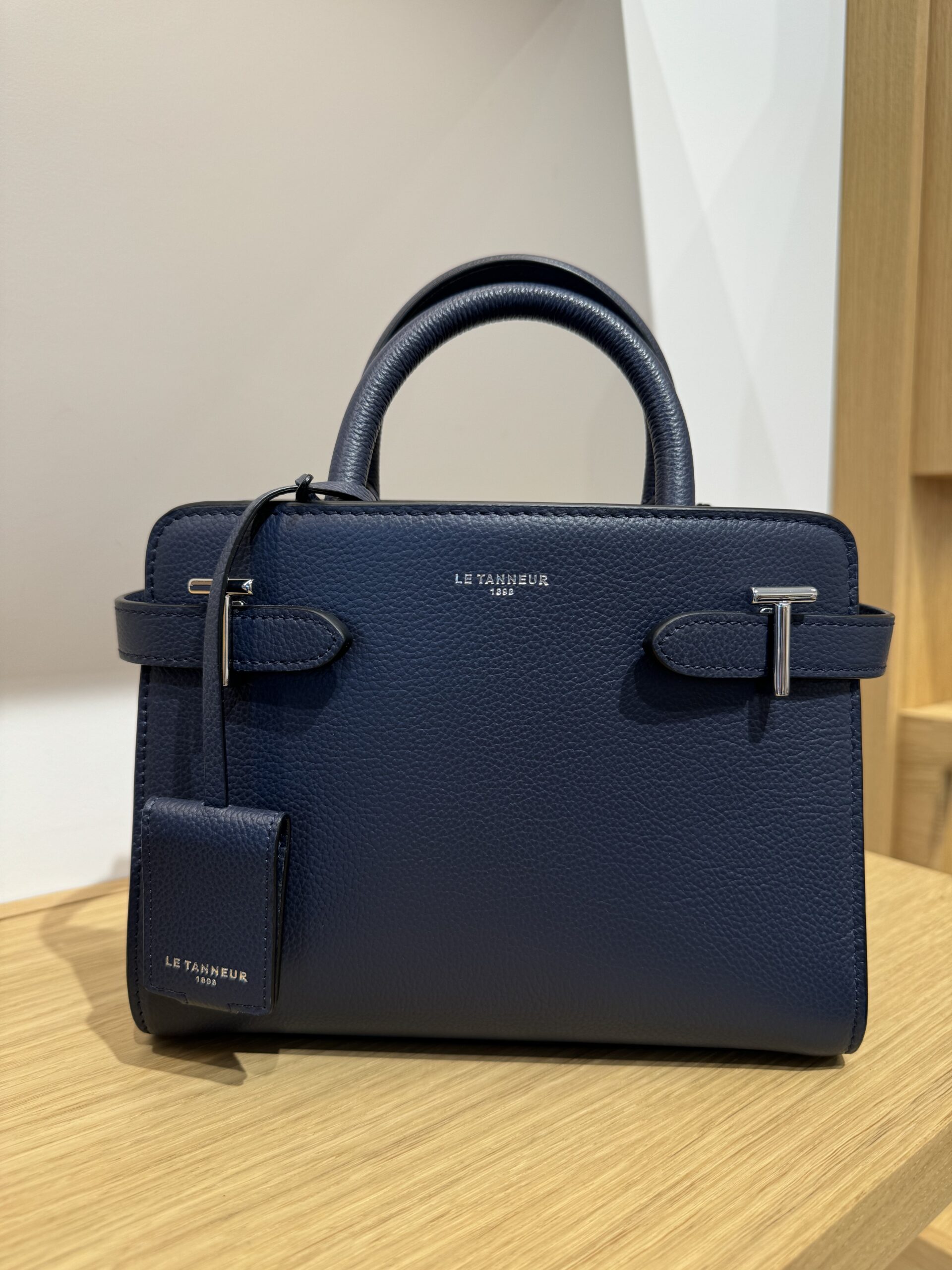 Le Tanneur leather handbags known for timeless French craftsmanship.Navy Le Tanneur sitting on a counter.