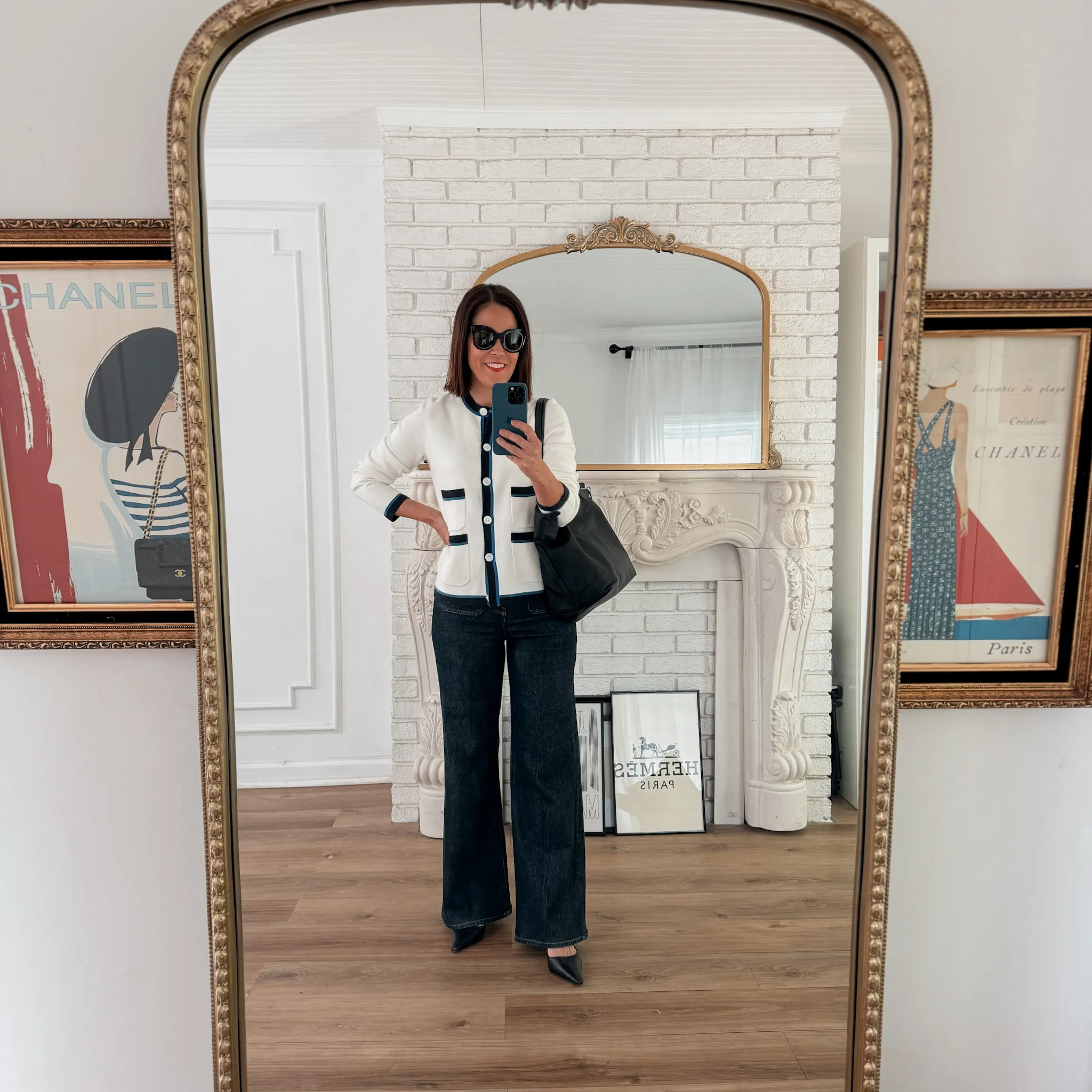 Woman looking in mirror wearing black and white cardigan with dark denim and slingbacks.