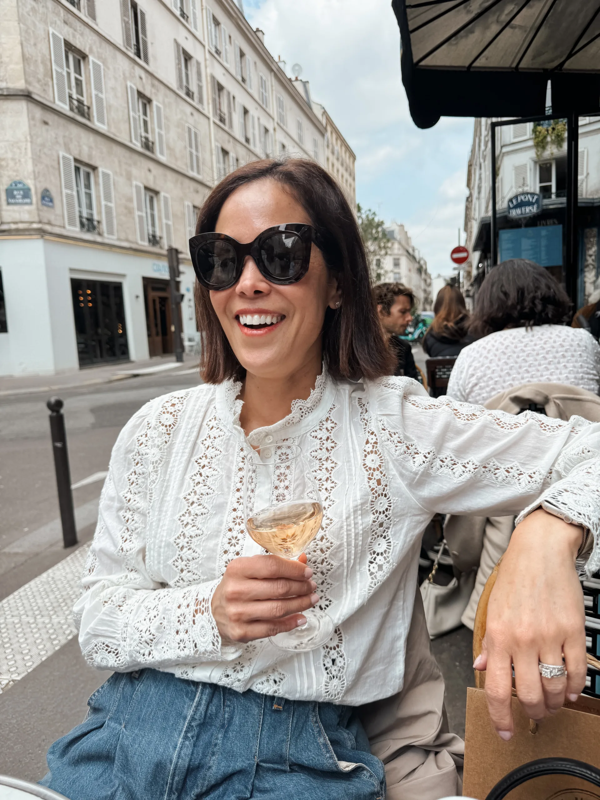 Woman wearing white blouse holding wine glass.