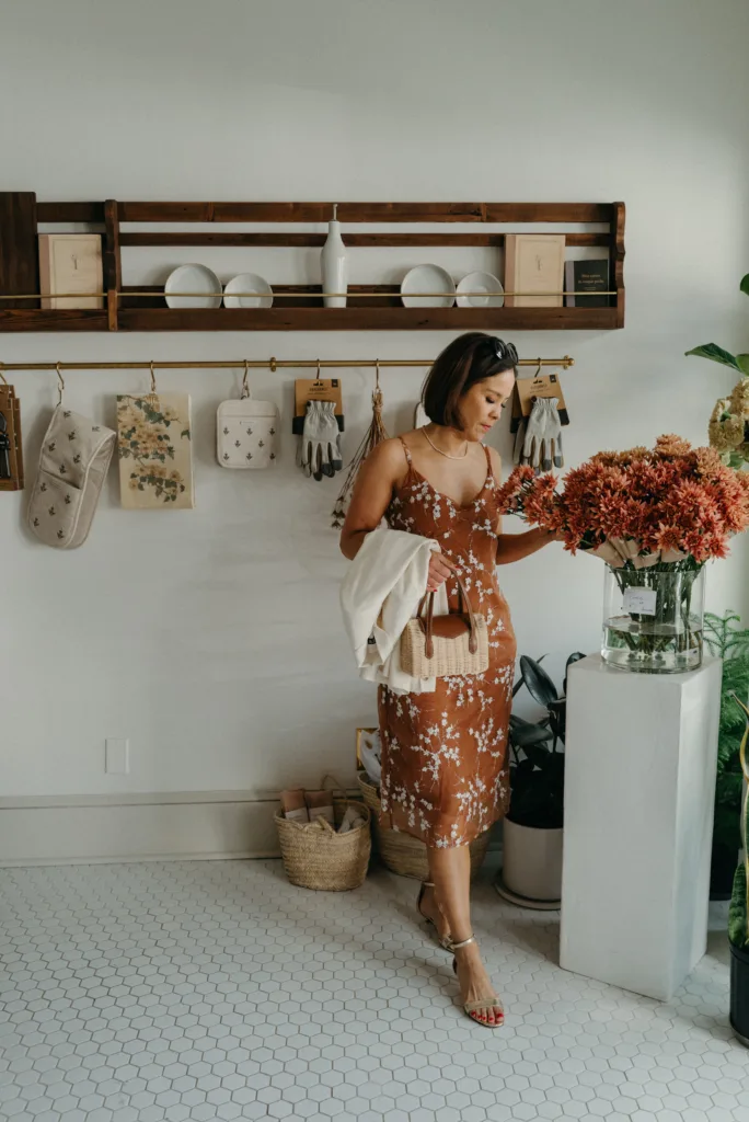 Woman wearing slip dress with blazer and gold sandals.