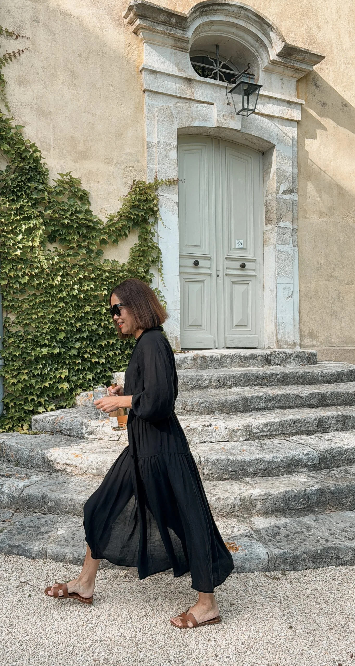 Woman walking in black dress with brown sandals in Provence.