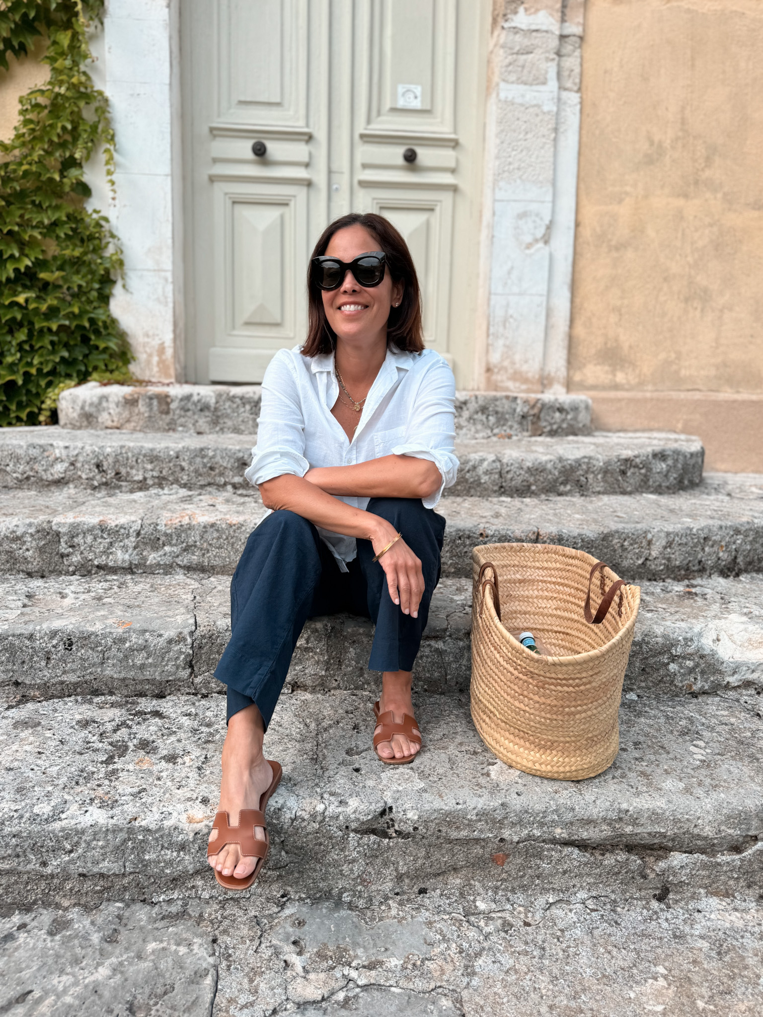 Woman sitting on steps with a basket bag in Provence.