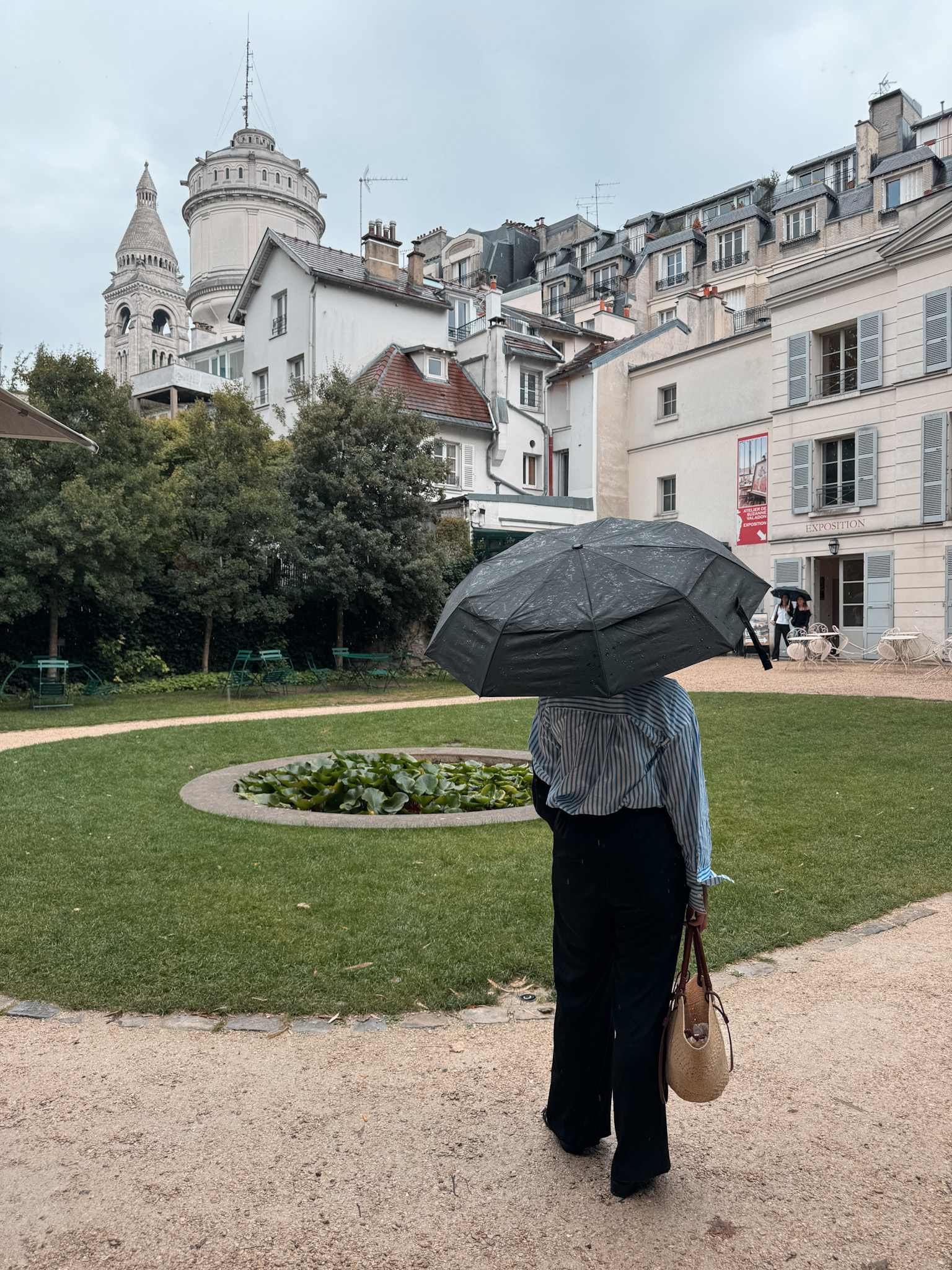 Woman with umbrella and button down top and shoes.