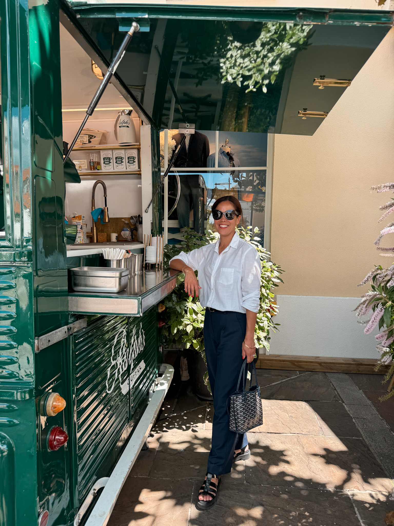 Woman wearing white button down with navy pants and flats.