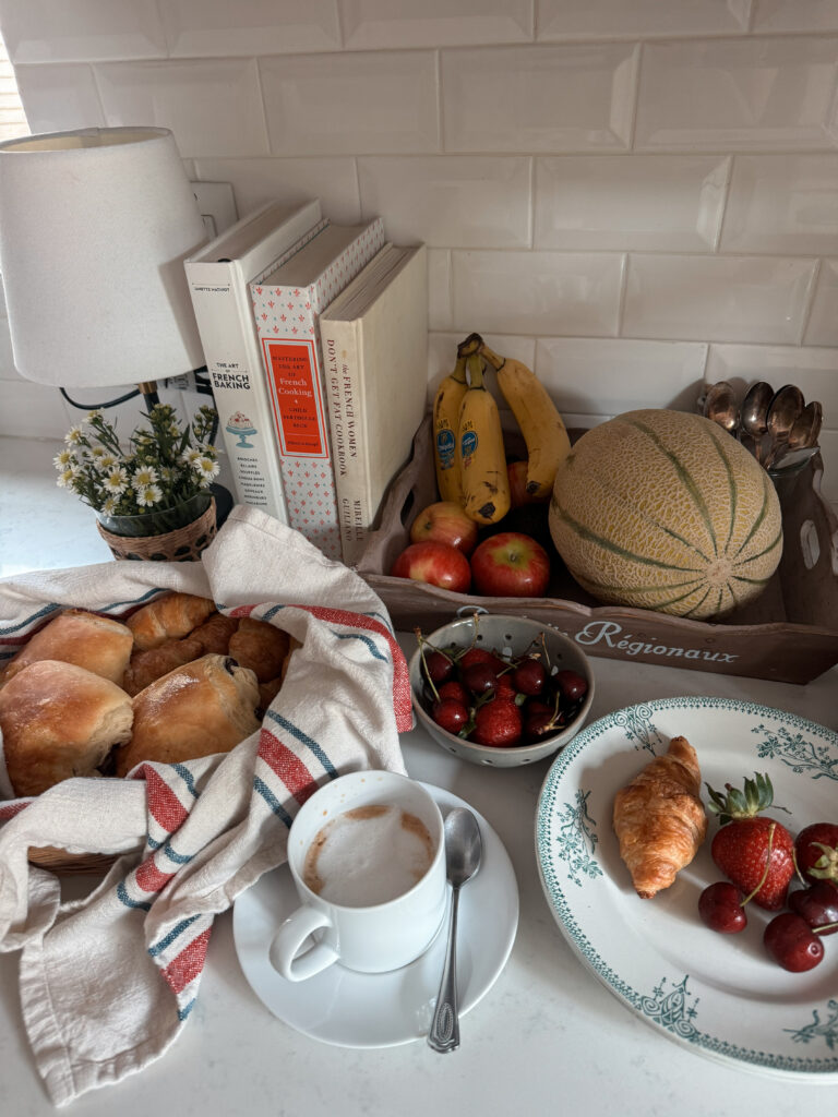Croissants in a basket Croissants in a basket with fruit in a brown tray with cookbooks in background.