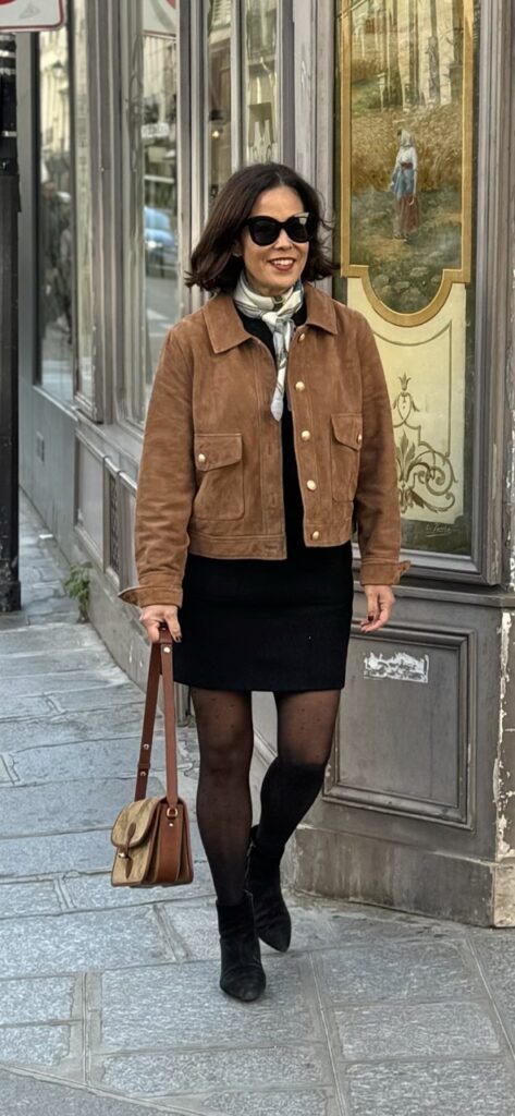 Woman wearing suede jacket with black skirt and black hose.