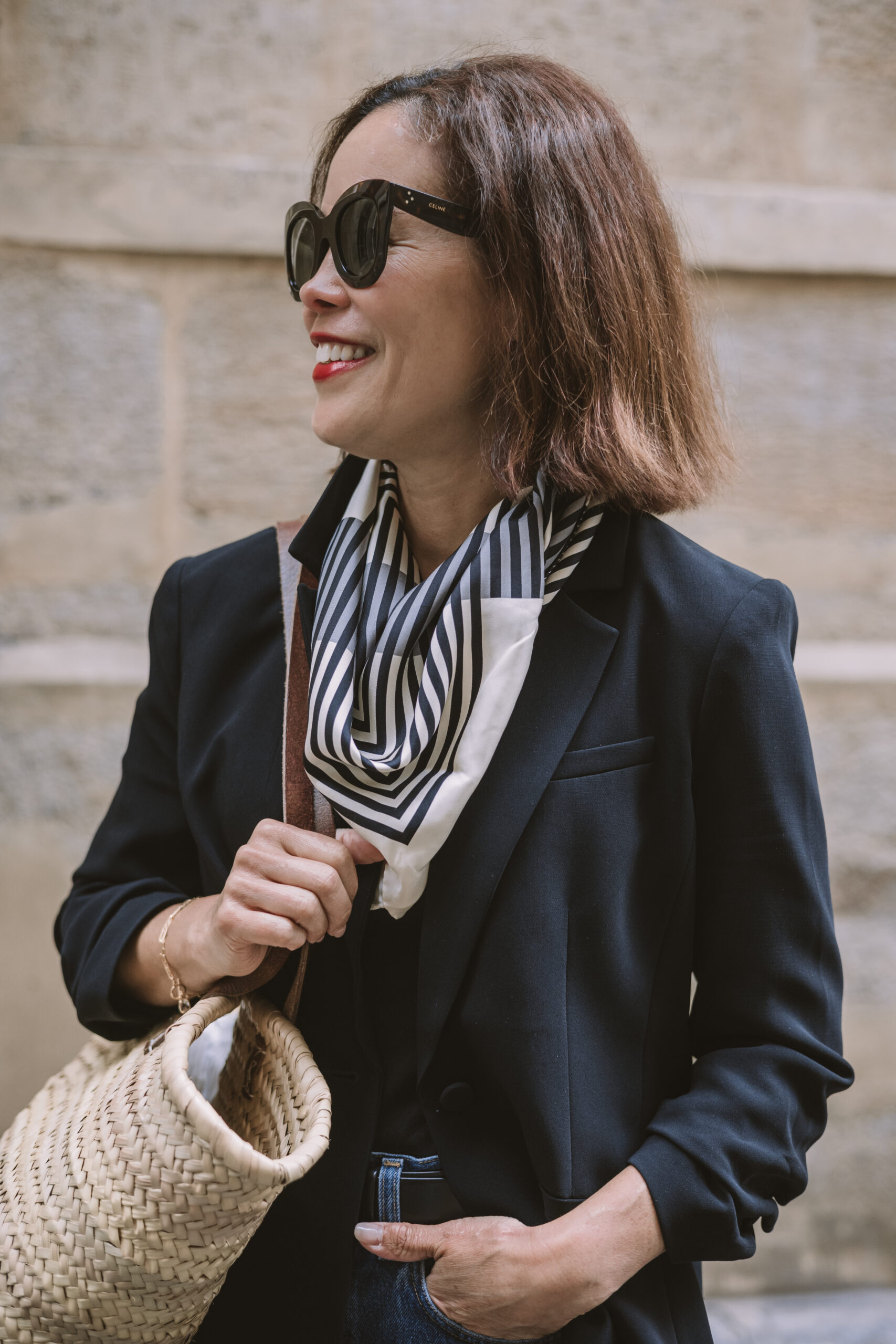 Woman wearing black blazer with black and white stripe scarf.