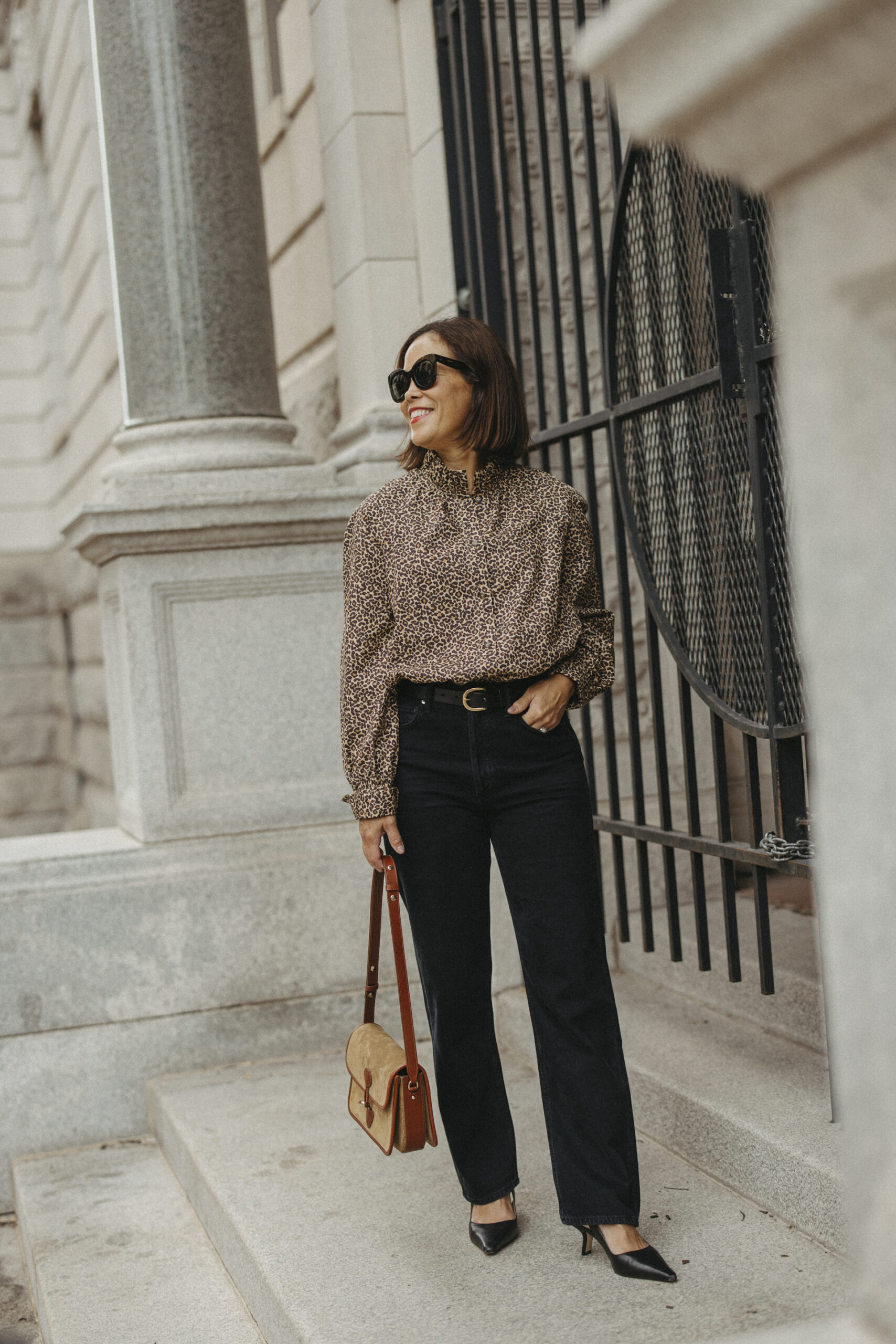 Woman wearing black jeans with animal print top and slingbacks.