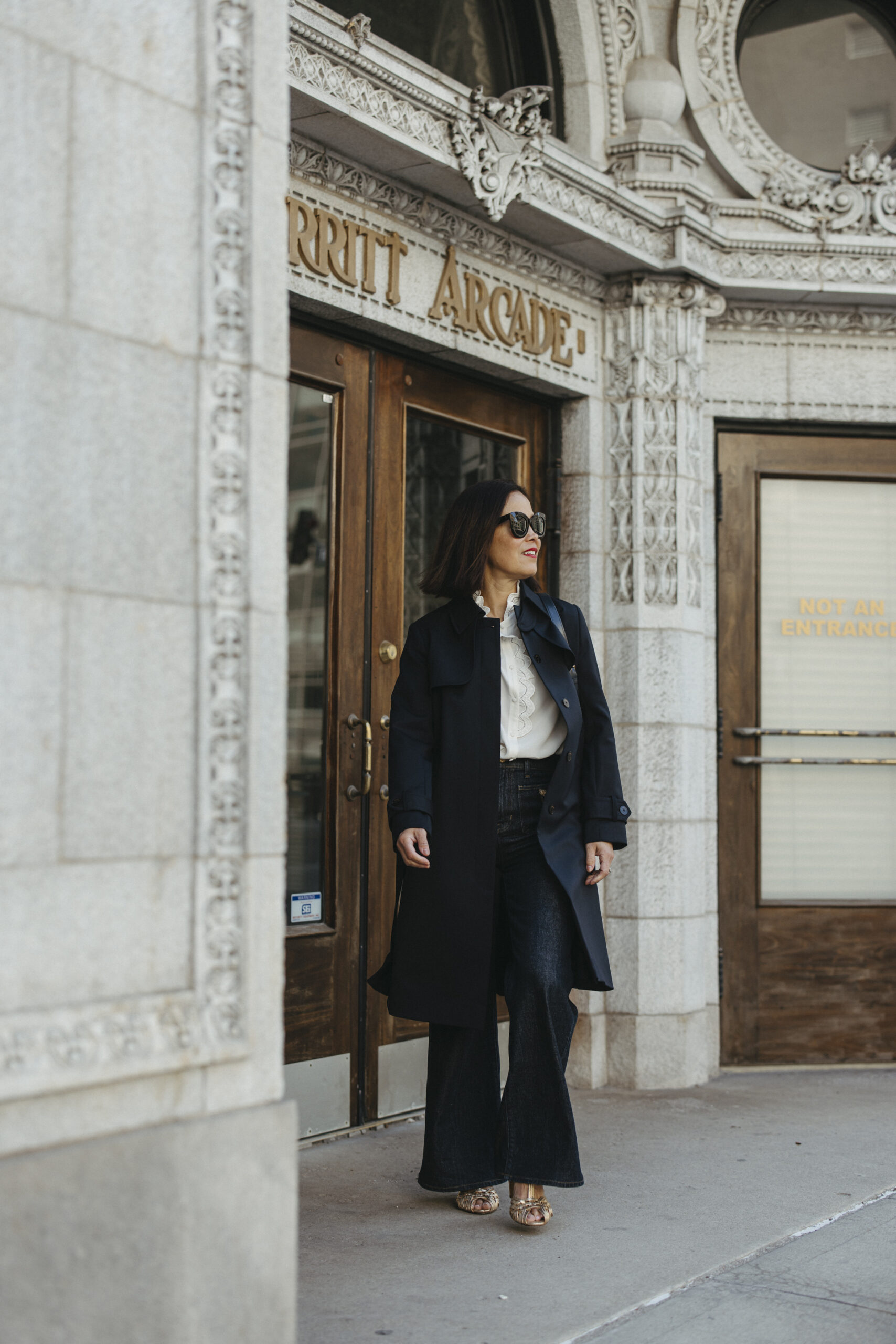 Woman wearing navy trench with jeans and top.