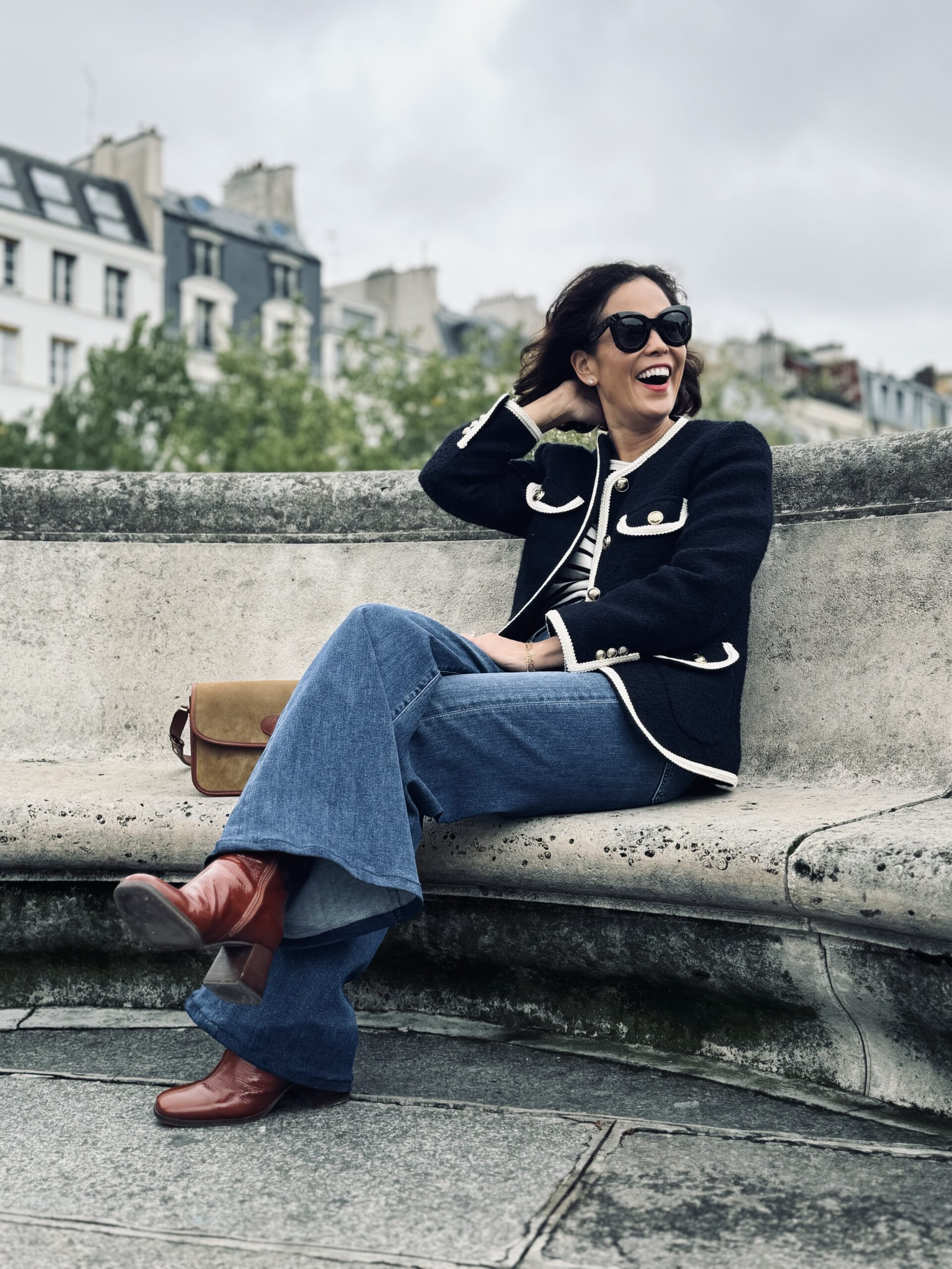 Woman wearing tweed jacket and jeans, with boots.