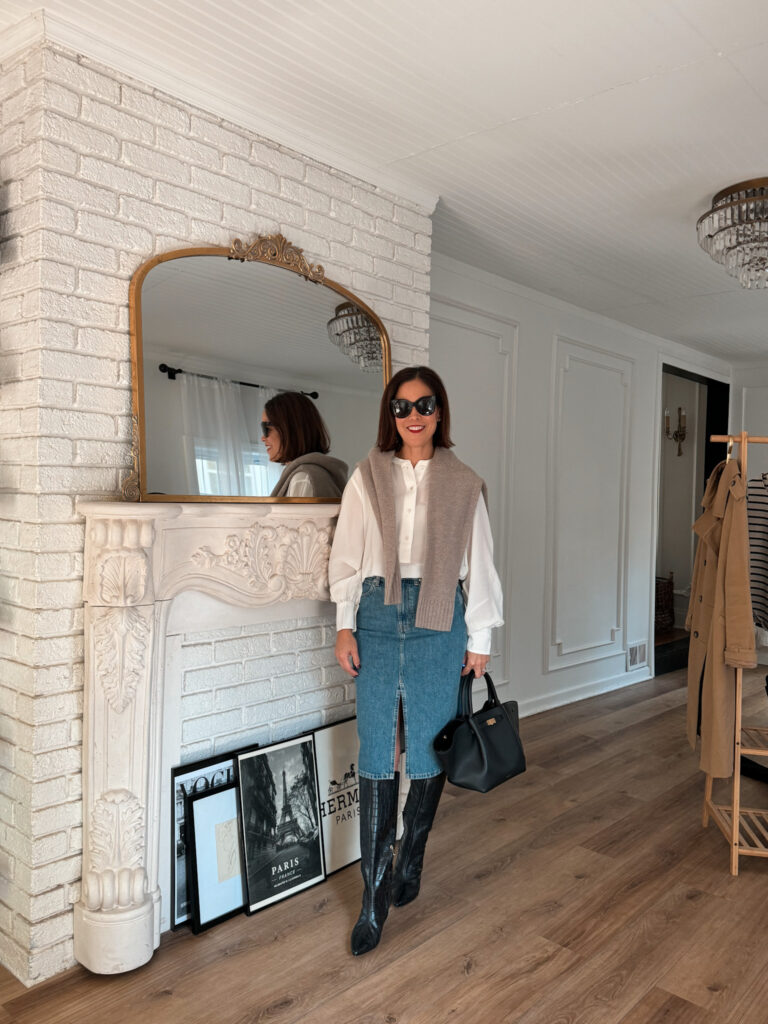 Woman wearing silk top with denim skirt and boots.