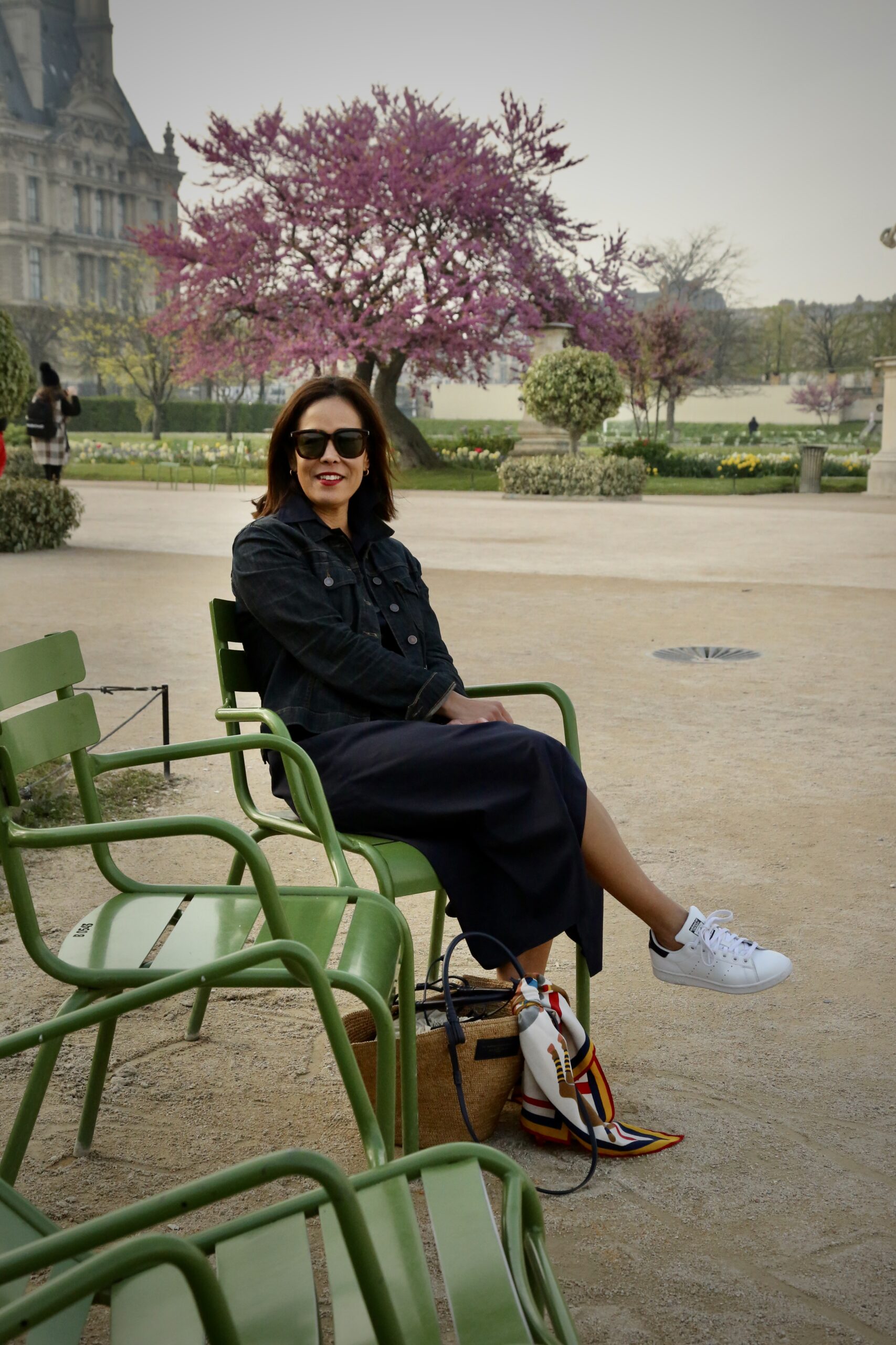 Woman wearing sneakers with denim dress mastering classic Parisian style. 