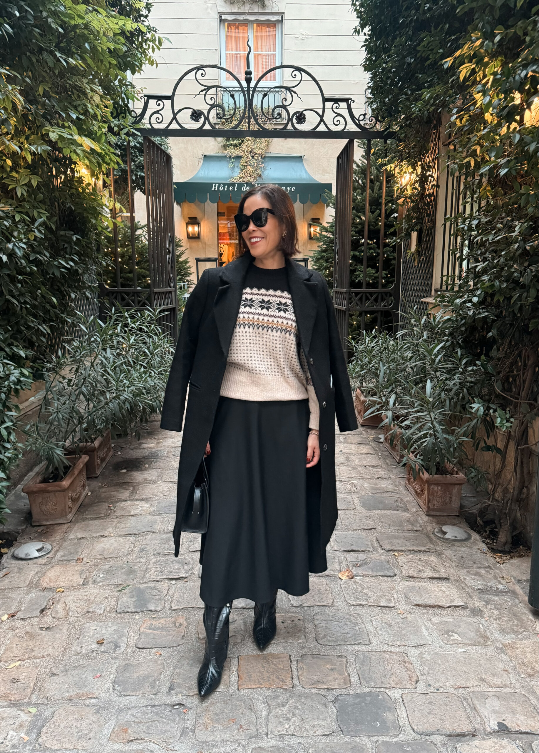 Woman in black coat and black skirt with sweater.