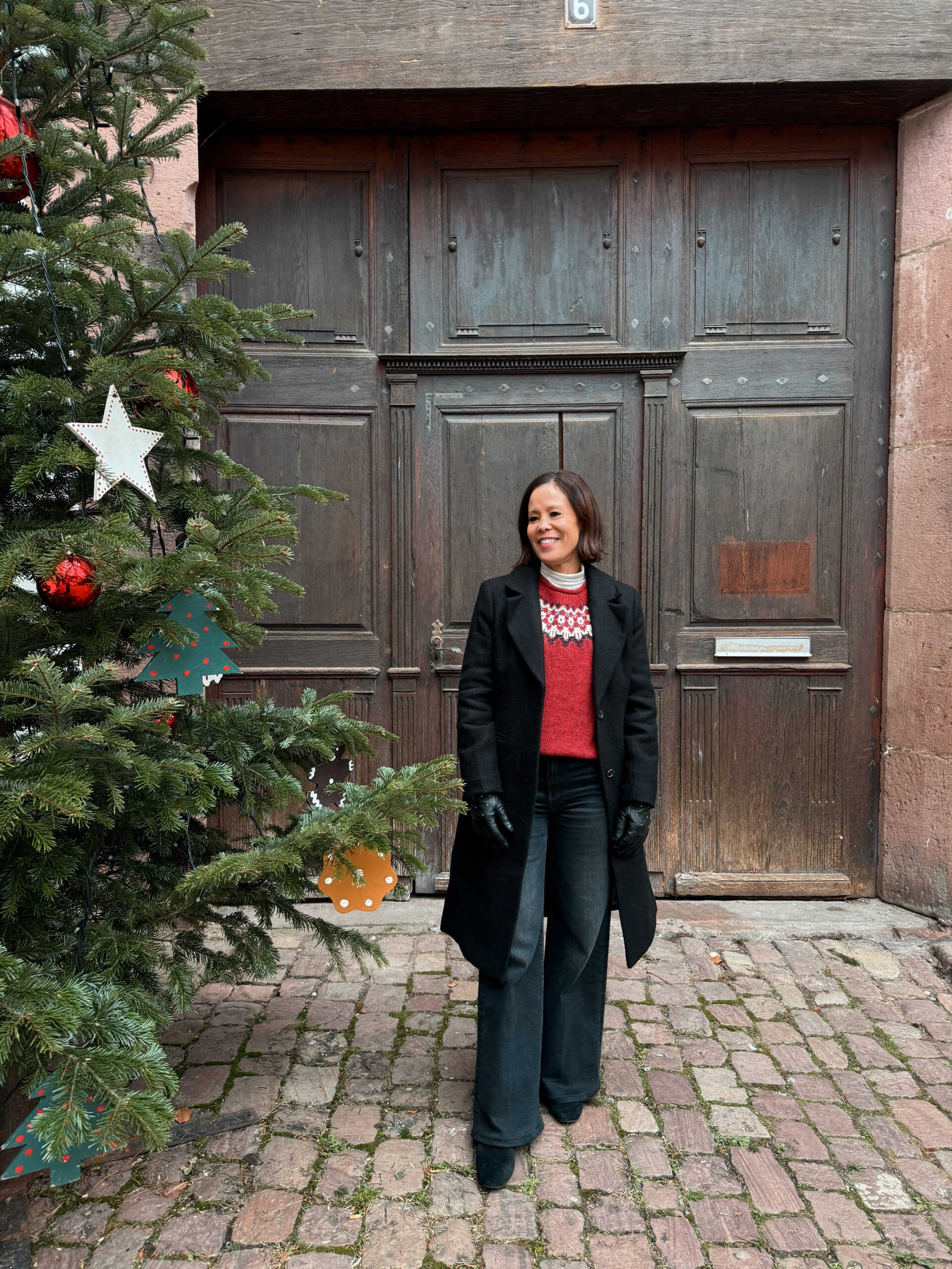 woman in black coat with black denim and red sweater.
