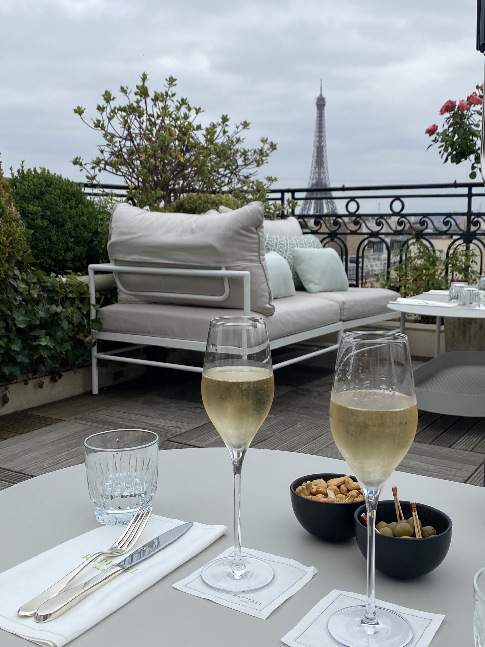 Two champagne glasses sitting on a table watching the eiffel tower.