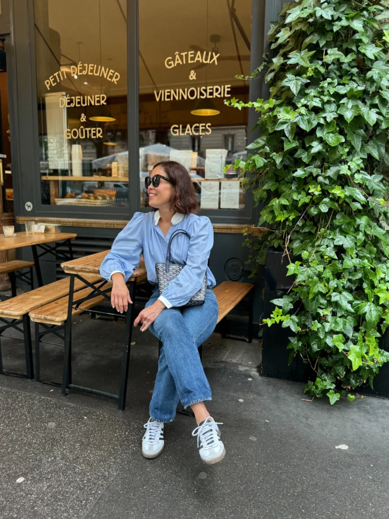 Lady sitting on a bench in front of a restaurant window. 
