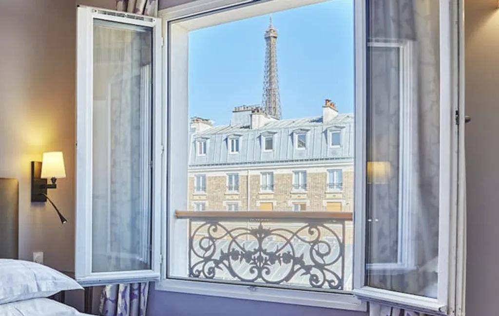 cheap Hotel room with windows open looking at Eiffel Tower in the distance.