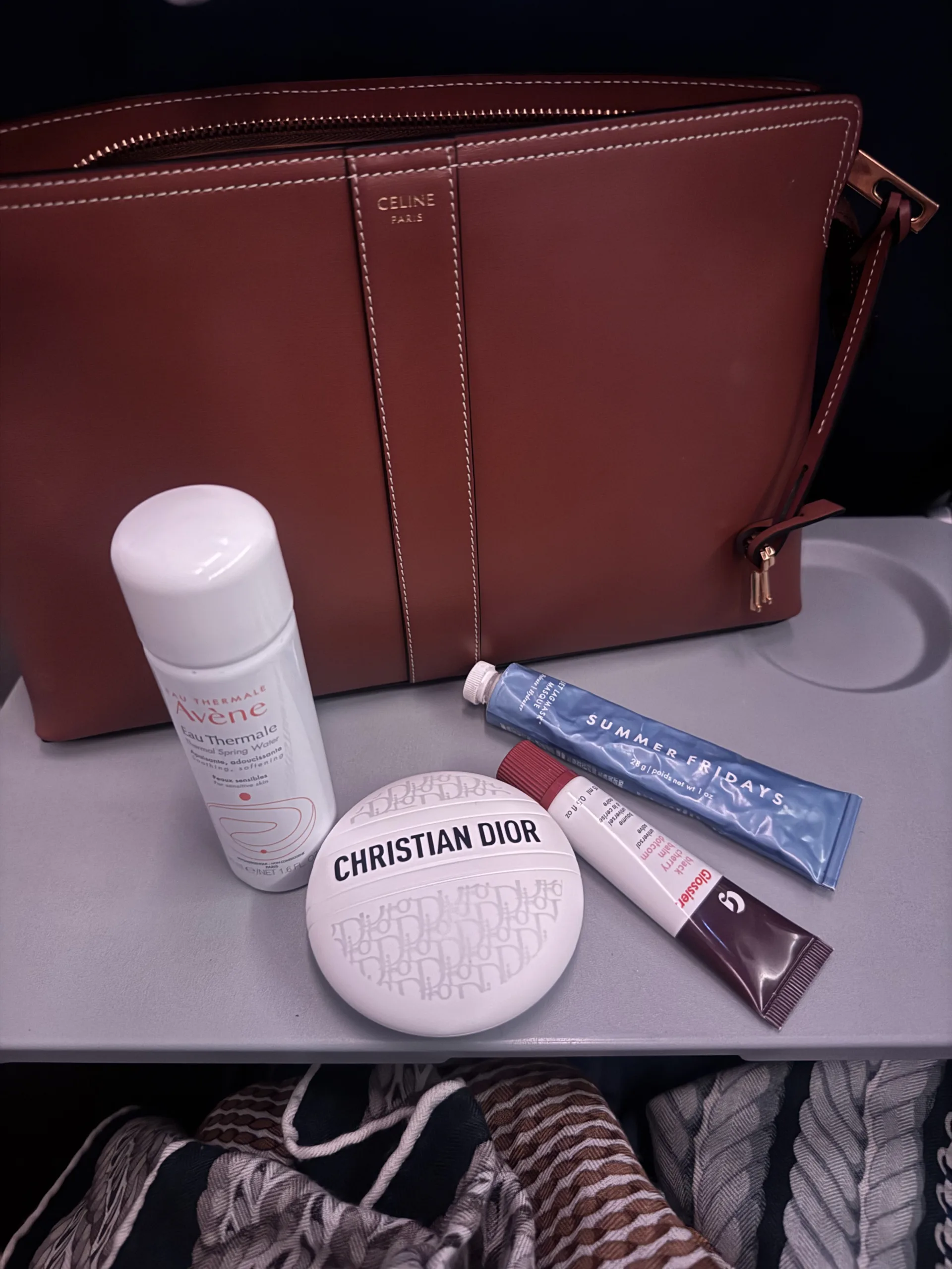 Skincare products sitting on a tray table for inflight essentials.