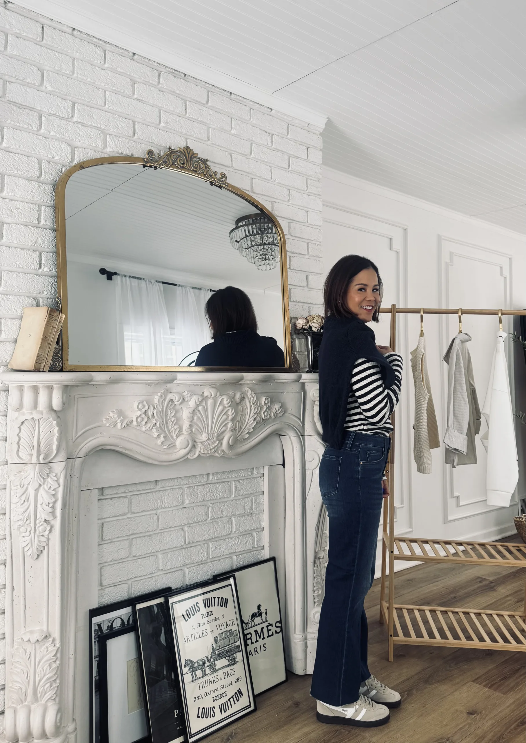Woman wearing stripe top with denim against a fireplace showing Evereve capusle pieces.