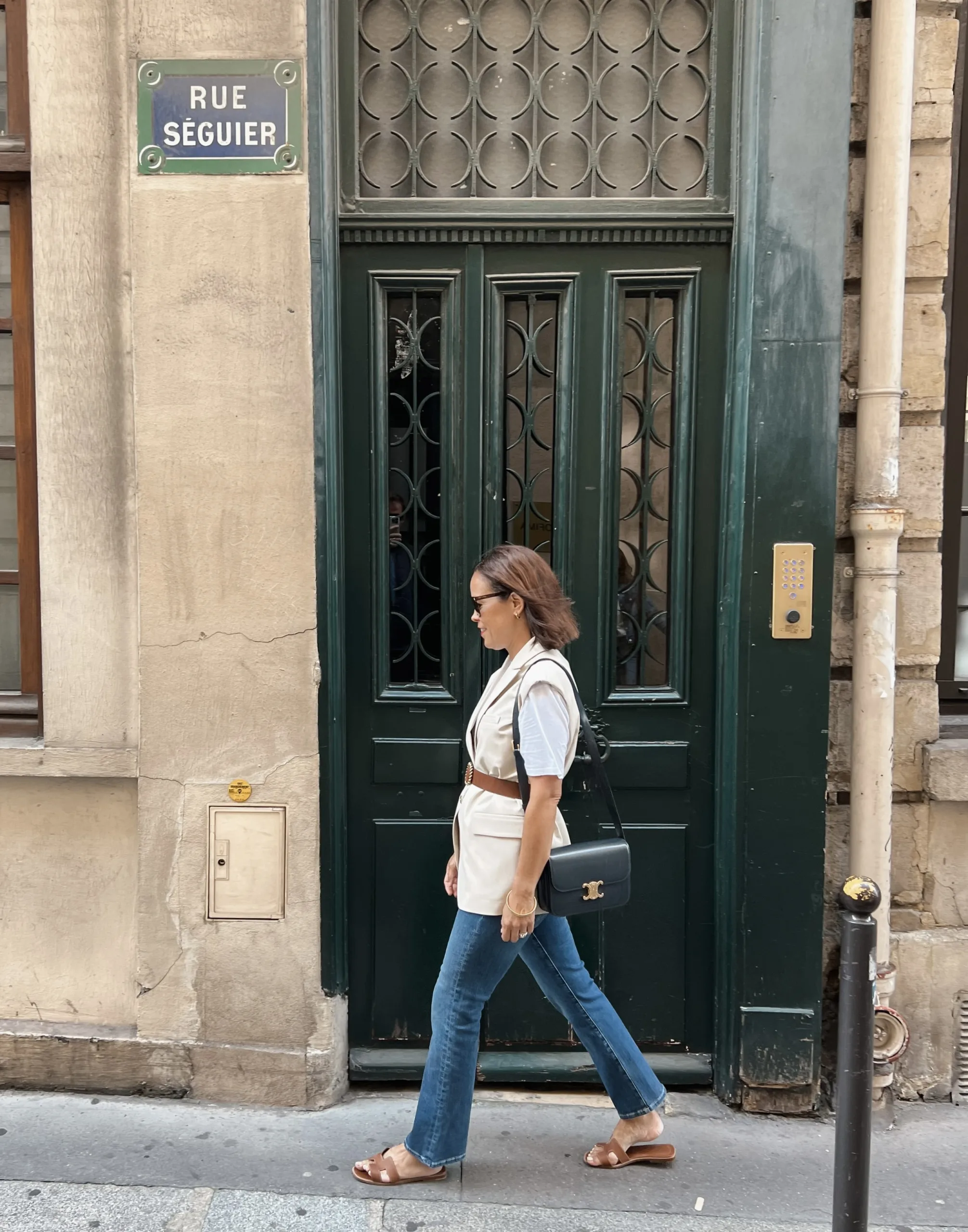 A woman wearing denim with sandals and a vest.