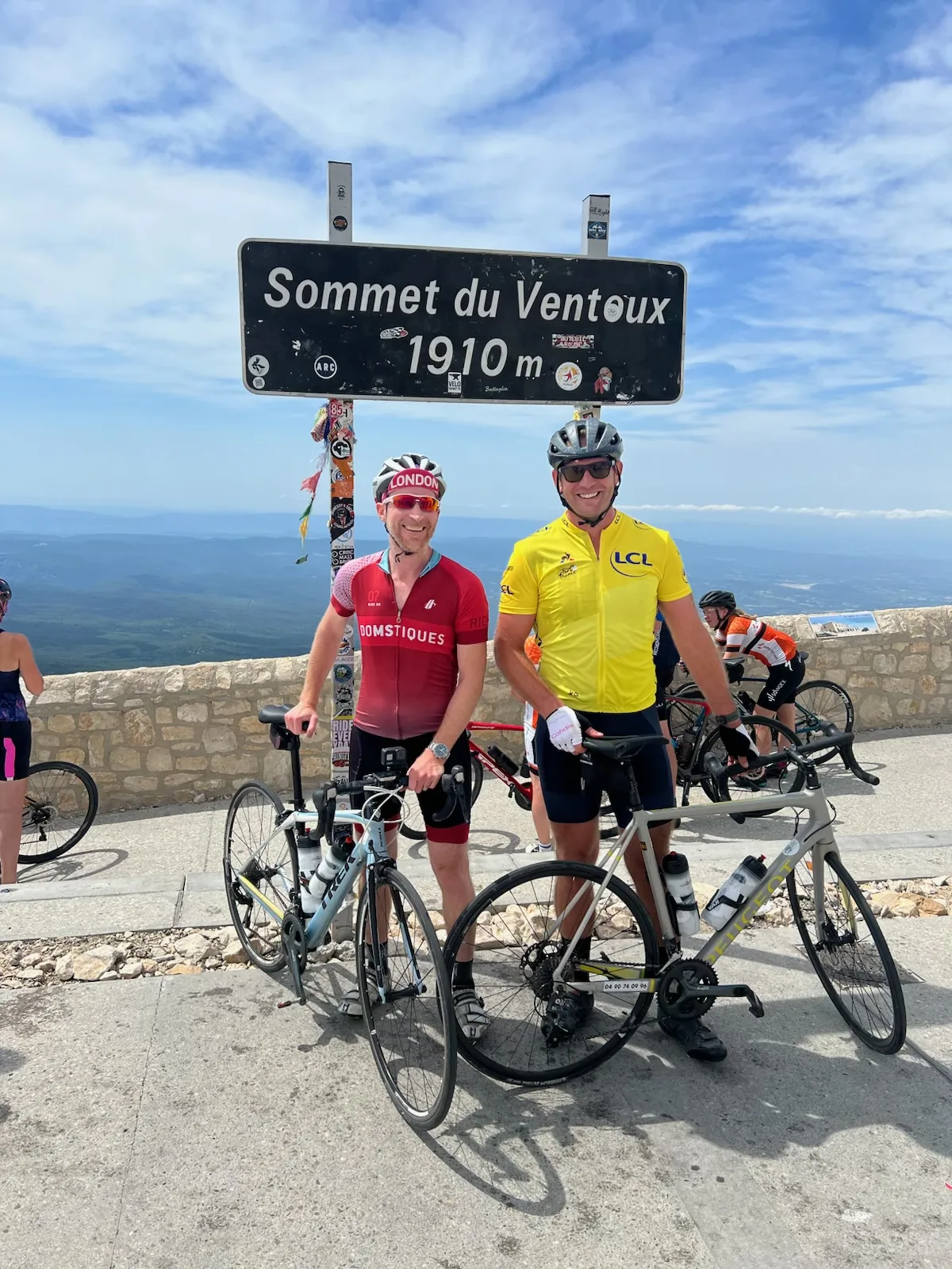 Two men at the top of Mont Ventoux with their bikes.