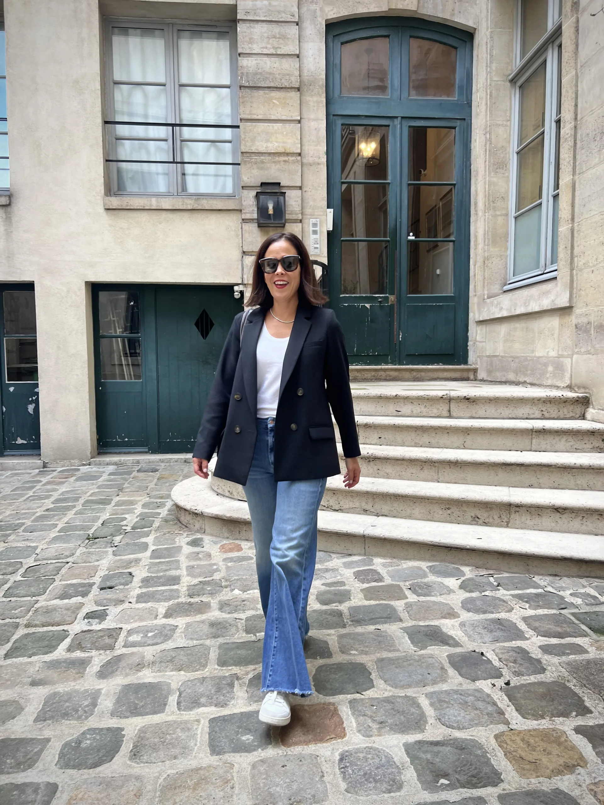 Woman wearing black blazer with sneakers and jeans.